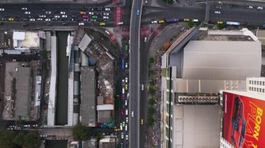 Bangkok şehir trafiğinin tepeden aşağı görüntüsü işlek kavşaklardan geçiyor, arabalar, otobüsler ve taksiler şehir sokaklarında geziniyor..