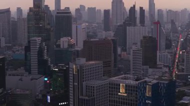 Alacakaranlıkta Bangkoks 'un ufuk çizgisini gösteren panoramik hava görüntüsü. Gösterişli gökdelenler ve aşağıdaki Asya şehirlerine hakim yüksek binalar..