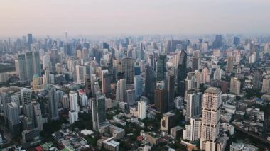 Bangkok, Tayland 'ın yoğun kentsel manzarasının havadan görüntüsü. Gün batımında sisli ufka uzanan sonsuz gökdelenler ve binalar..