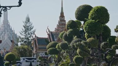 Geleneksel Tayland mimarisi ile Bangkok 'taki Grand Palace. Manikürlü bahçeler ve ağaçlar ön planda..