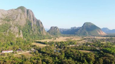 Karanlık dağ siluetlerinin arkasında altın güneş batıyor. Güneydoğu Asya manzarasında altın saat boyunca turuncu gökyüzü.