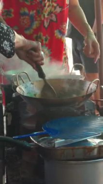 Tavadan yükselen buharla yerel mutfağın özünü yakalayan bir sokak yemeği satıcısının yakın çekimi..