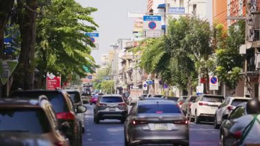 Bangkok şehir merkezinde trafik ve binalarla şehir caddesinin el kamerasıyla çekilmiş görüntüleri. Güneydoğu Asya 'da ulaşım ve şehir manzarası.