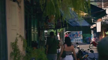 Bangkok, Tayland 'ın geleneksel bir mahallesinde kalabalık ve dar bir sokakta yürüyen insanların el kamerası görüntüleri..