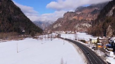 Kış boyunca dağlarla ve mavi gökyüzüyle Avusturya 'nın Saalbach kentindeki karlı vadide dönen alp yolunda giden arabaların geniş perspektifi..