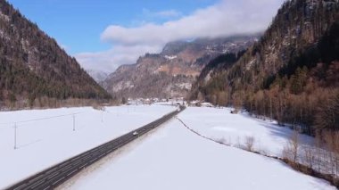 Saalbach yakınlarındaki Avusturya Alpleri 'nde karlı dağ yolunda giden arabaların hava manzarası güneşli bir kış gününde karlı tarlalar ve ormanlarla kaplı..