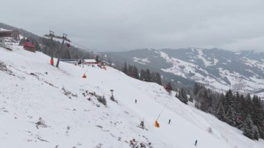 İnsanlar soğuk bir kış günü Avusturya Alplerinde kayak kaldırarak karlı bir yamaçta eşsiz bir üç ayaklı hava perspektifinden kayıyorlar..