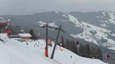 Avusturya Alpleri 'nde kış tatilinde insanlar yamaçta kayak yapıyor ve dağ otelinde teleferik kullanıyorlar..