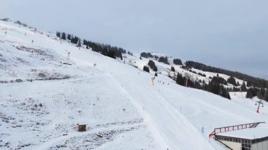 Alpler 'de bir dağ kayak merkezinin üzerinde uçan statik hava görüntüsü. Sandalyeler ve kış günü kayak yapan çok az insan var..