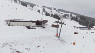 İnsanlar Alp Otel 'deki karlı yamaçlarda teleferik kullanırken kış tatillerinde dağa çıkıyorlar..
