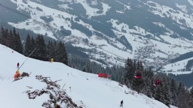 Saalbach 'taki Avusturya Alpleri' nde yamaçtan inen kayakçı ve gondolla kayak merkezi yükseliyor..