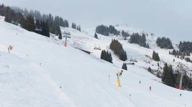 İnsanlar Alpler 'deki kış tatillerinde Alp dağlarında bir teleferikle karlı bir yamaçta kayak ve snowboard yapıyorlar. Hem de eşsiz bir hava perspektifinden..