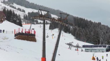 Kayak teleferiği kayakçıları Alpler 'deki kış tatili tatil köyünde karlı dağ yamacına taşır..