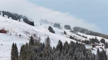 Karlı bir dağdaki kayak merkezinin havadan görünüşü. Alplerdeki sisli bir orman arazisinde kış boyunca başkanlar hareket ediyor..