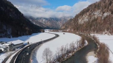 Saalbach, Avusturya 'da güneşli bir günde, karlı bir Alp Vadisi manzarasının içinden geçen arabaların yüksek açılı görüntüleri..
