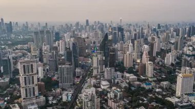 Bangkoks silueti üzerinde günden geceye hızlı geçiş, hareketli şehir yaşamını, aydınlatılmış otoyolları ve Tayland başkentinin modern şehir mimarisini gözler önüne sermek.