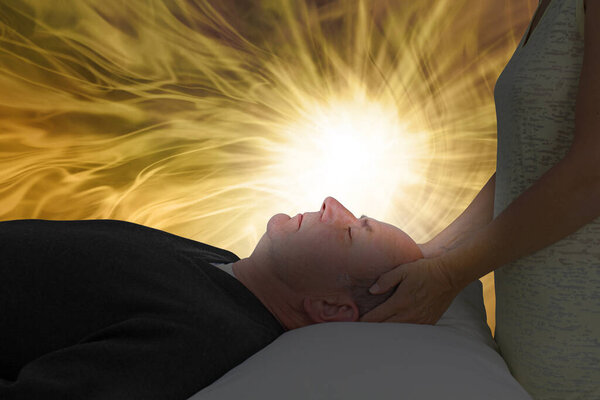 Channelling Beautiful Golden Healing Energy - самка с руками, нежно держащими человеческую голову, лежащими на спине, с ярким белым светом, освещающим его лицо в окружении золотого света и копировального пространства