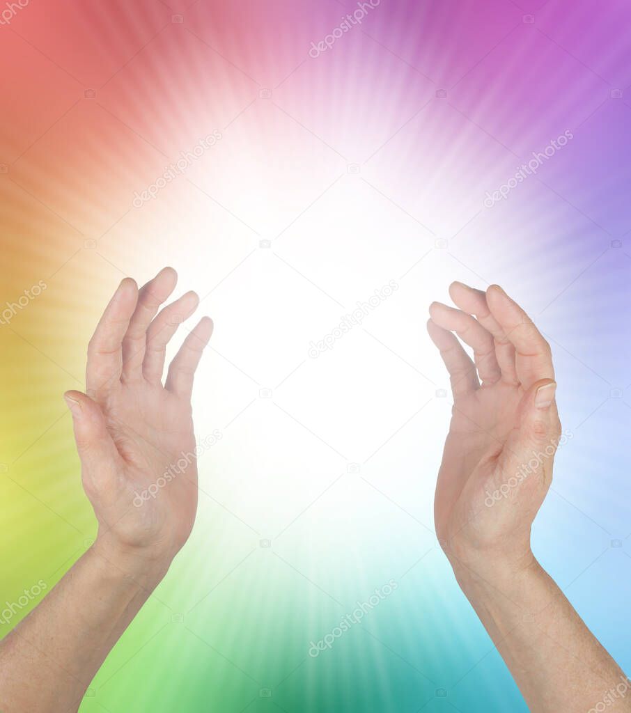 Healing Rainbow Energy Phenomenon and White Light - female hands with a bright white orb between and rainbow coloured aura with copy space