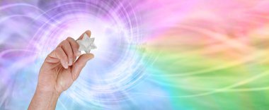 Bir Merkabah 'ın yaydığı inanılmaz enerji, beyaz bir kuvars tutan erkek eli Merkabah parlatılmış kristal, çarpıcı renkli bir gökkuşağı girdabı yayıyor.