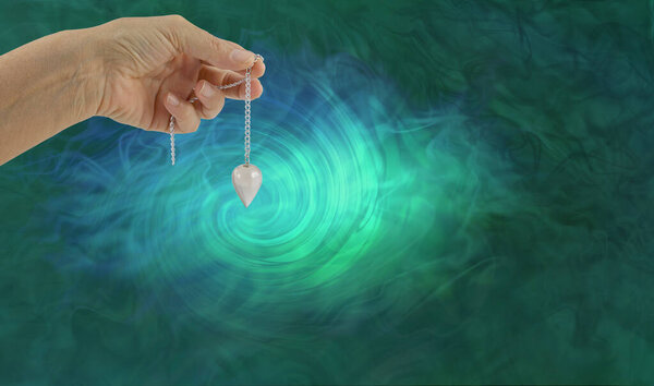 Dowsing Pendant Vortex Message Background - женская рука, держащая маятник кварца радионики против зеленого синего вихря вихревого энергетического поля спирали с копировальным пространством