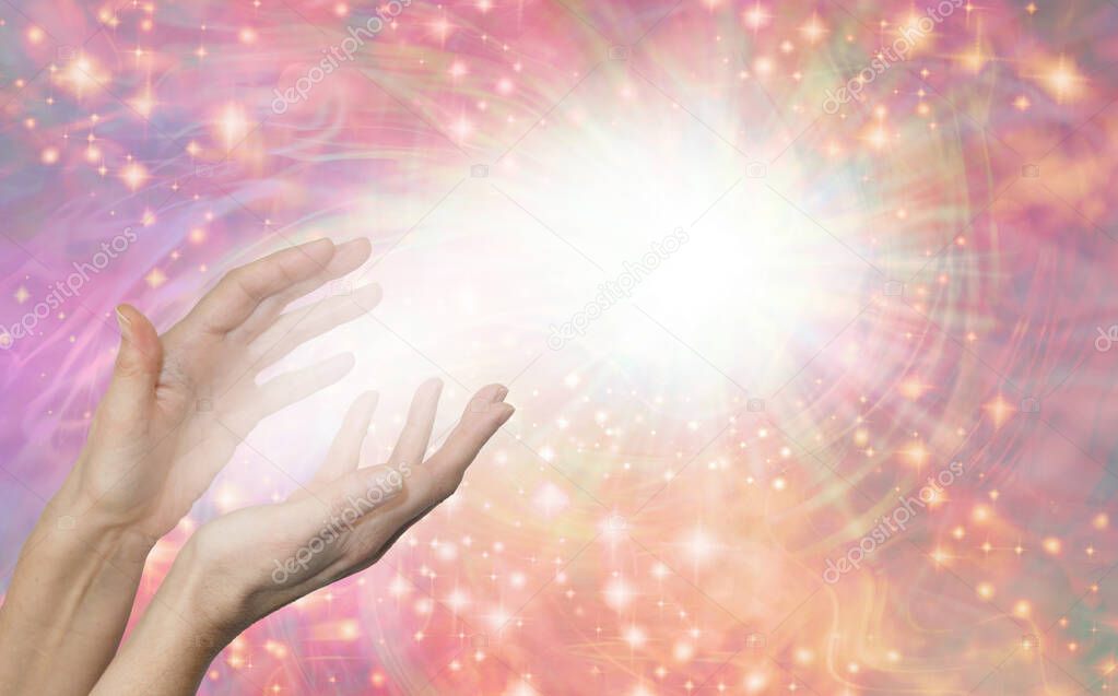Sensing Scalar Healing Energy Field - Female hands reaching up into ball of white light against a rotating sparkling peach and pink background with copy space