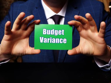 Adamın elinde yeşil kartvizit var. Bütçe Varyansı ifadesi var. Grey Backgroun 'a yakın çekim.