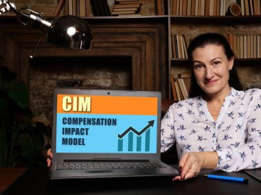 Ekran arka planında CIM COMPENSATION IMPACT MODEL simgesi olan dizüstü bilgisayarı gösteren kadın, iş konseptinde başarı