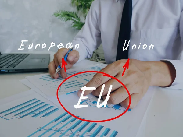 Conceptual photo about EU European Union with written acronym. Senior Man Checking A Document on background