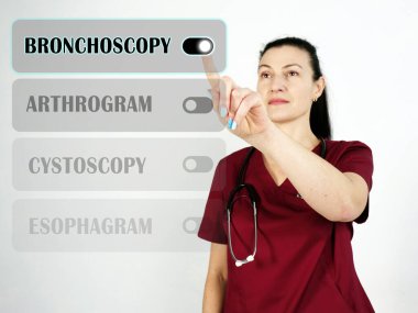  Mönüde BRONCHOSCOPY metni. Hekim cep telefonunda bir şey arıyor.