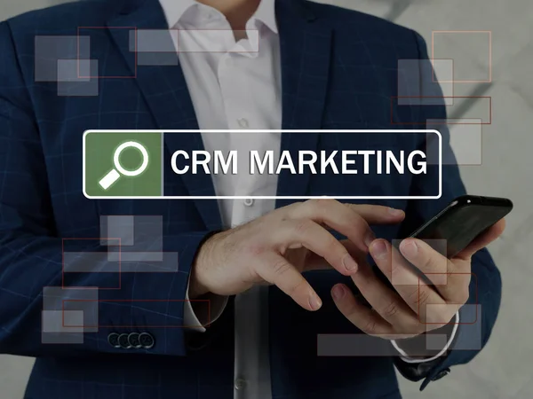 CRM MARKETING Customer Relationship Management inscription on the screen. Close up Manager hands holding black smart phone. The goal of CRM marketing is to improve and optimize customer relationship