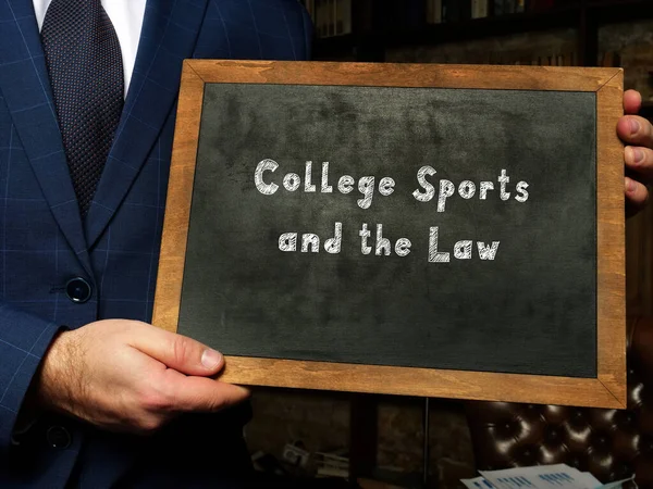 Chalkboard in a hand with phrase College Sports and the Law . Horizontal shot