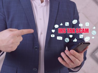 Arama çubuğunda IRS Vergi SCAM metni. İş adamı cep telefonuna bakıyor. Milli Gelirler İdaresi 'nin taklit kameraları vergi memuru gibi davranarak Amerikan vergi mükelleflerini hedef alan dolandırıcıları içeriyor.