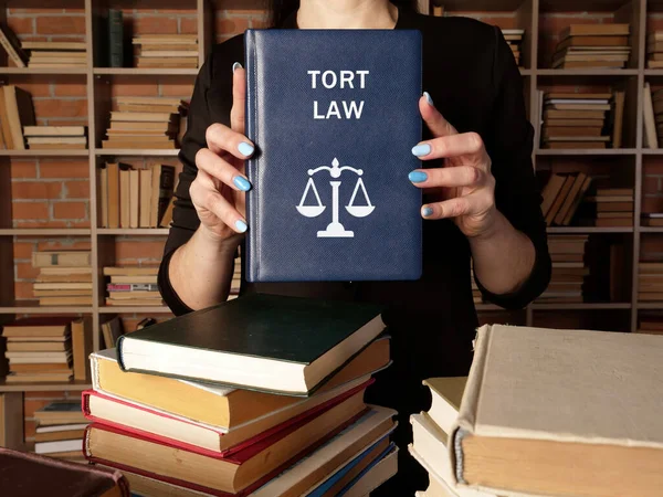 Lawyer holds TORT LAW book. A tort occurs when someone commits a wrong against another perso