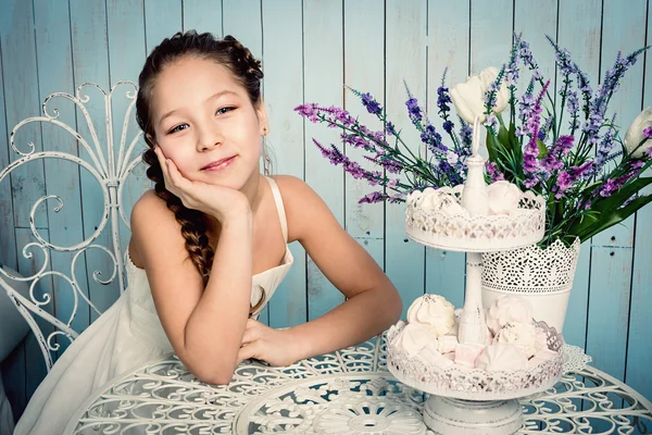 Dívka s sladkosti na stůl — Stock fotografie