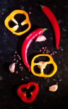 Siyah bir taşın üzerinde farklı renkte biberler