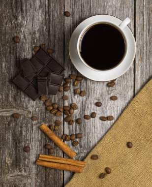 Kahve ve kahve çekirdekleri, çikolata ve tarçın ahşap bir masada.