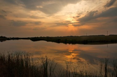 Gölün ya da göletin üzerindeki bulutlarda gün batımı