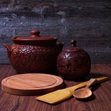 Mutfak masasında hala hayat dolu kil, ahşap kap ve tahta kaşıklar var.