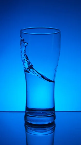 青い背景にガラスと水のスプラッシュ — ストック写真