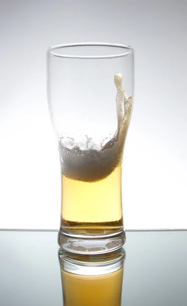A splash of beer with foam in a beer glass
