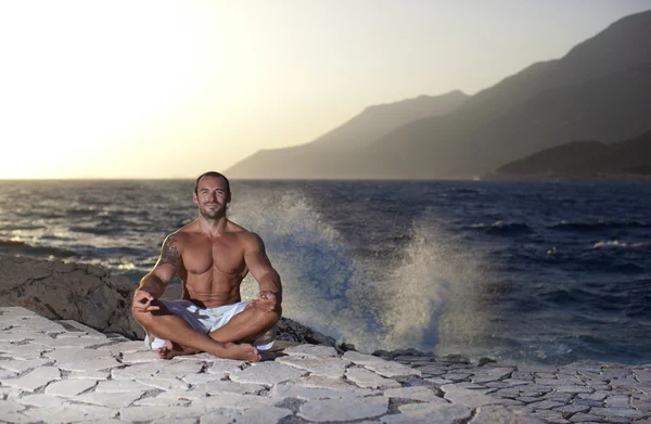 Muscular man meditating in a yoga pose