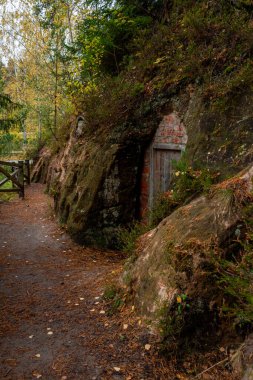 Litvanya 'nın Ligatne kentindeki Cave Rock' taki (Lustuzis) mahzen kayalıkları, malzeme depolamak için kullanılan bulutlu sonbahar günlerinde