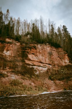Letonya 'da bulutlu bir sonbahar gününde Amata nehri kıyısındaki Dzilna kayası