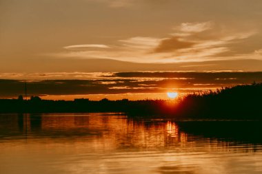 Sıcak yaz akşamı Letonya 'daki Lielupe nehrinin üzerinde renkli ve yoğun bir gün batımı.
