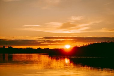 Sıcak yaz akşamı Letonya 'daki Lielupe nehrinin üzerinde renkli ve yoğun bir gün batımı.