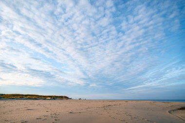 Kumda mavi gökyüzü ve arkasında beyaz bulutlar olan ayak izleri. Letonya, Karnikava yakınlarındaki Baltık Denizi kıyısı