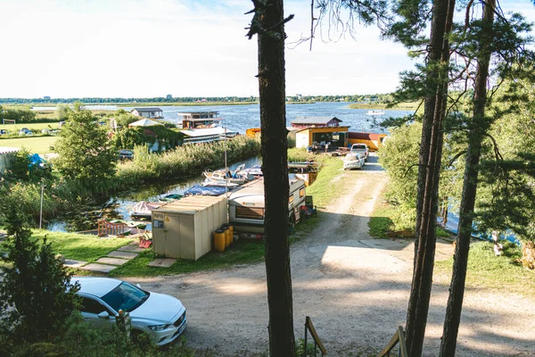Fishing camp with boats and cars parked in the middle of the forest by the Lielupe river in Latvia