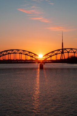 Avrupa Birliği 'nin en yüksek kulesine sahip Daugava nehri ve demiryolu köprüsü üzerinde renkli gün doğumu - Riga, Letonya' daki Radyo ve TV kulesi
