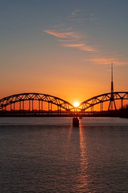 Avrupa Birliği 'nin en yüksek kulesine sahip Daugava nehri ve demiryolu köprüsü üzerinde renkli gün doğumu - Riga, Letonya' daki Radyo ve TV kulesi