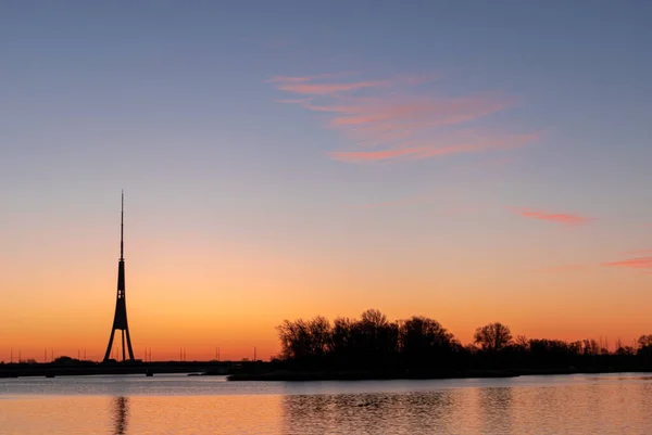 The tallest tower in the European Union - Radio and TV tower in Riga, Latvia during colorful sunrise over the Daugava river